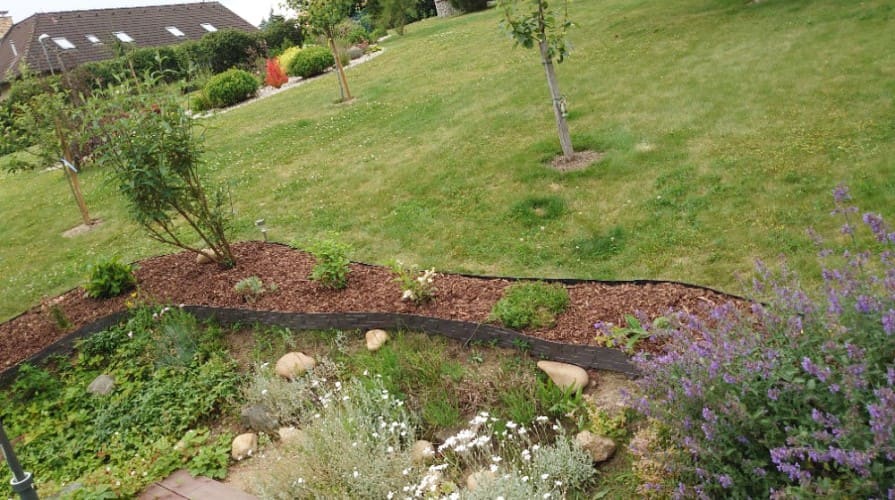 Ratanové palisády oddělující okrasný záhon od trávníku